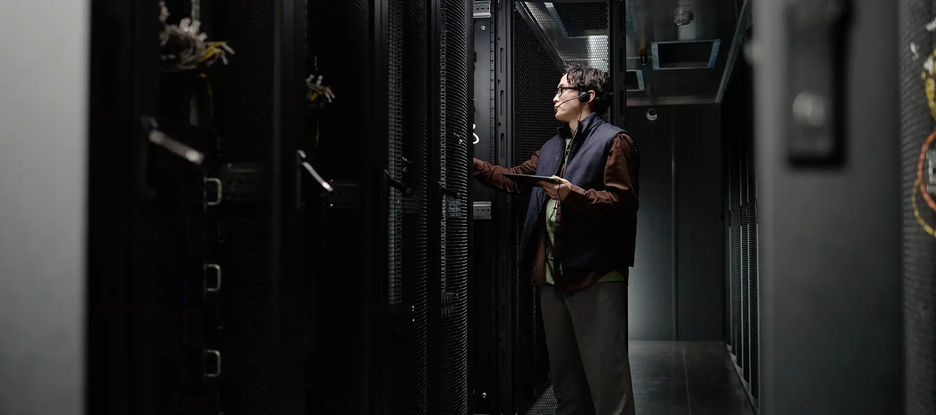 A man in a data center carefully inspecting the contents of a server rack