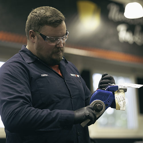 A HYTORC employee holding an MXT+ Hydraulic Torque Wrench with a reaction arm.