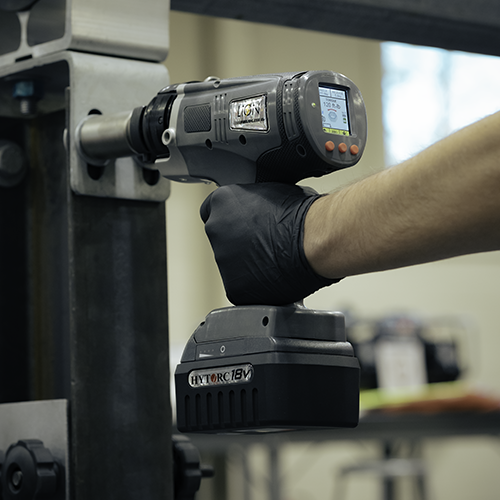 A gloved hand operating a LION GUN Dual Speed Electric Torque Tool