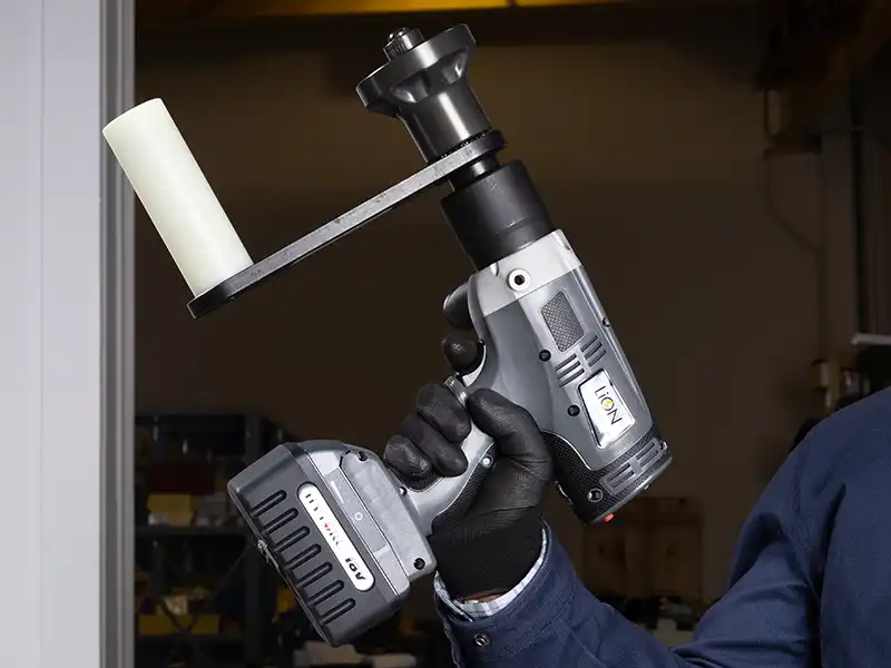 A gloved hand holds the LION GUN Electric Torque Tool, ready to tighten wheel nuts.